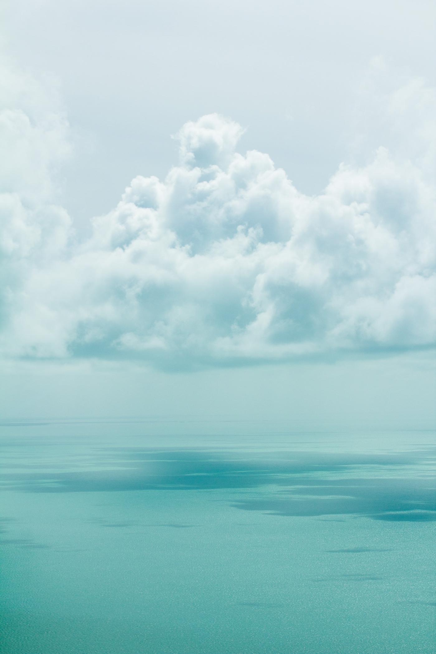 Low cloud sitting directly on a still, pale green sea
